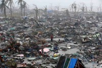 People stood among the ruins of houses destroyed by Typhoon Haiyan in Tacloban, Philippines, a city of about 220,000. Photo: Erik De Castro/Reuters